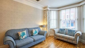 A room with a blue sofa and a plaid sofa, both with decorative pillows. - Host & Stay | Allium House (Whitby)