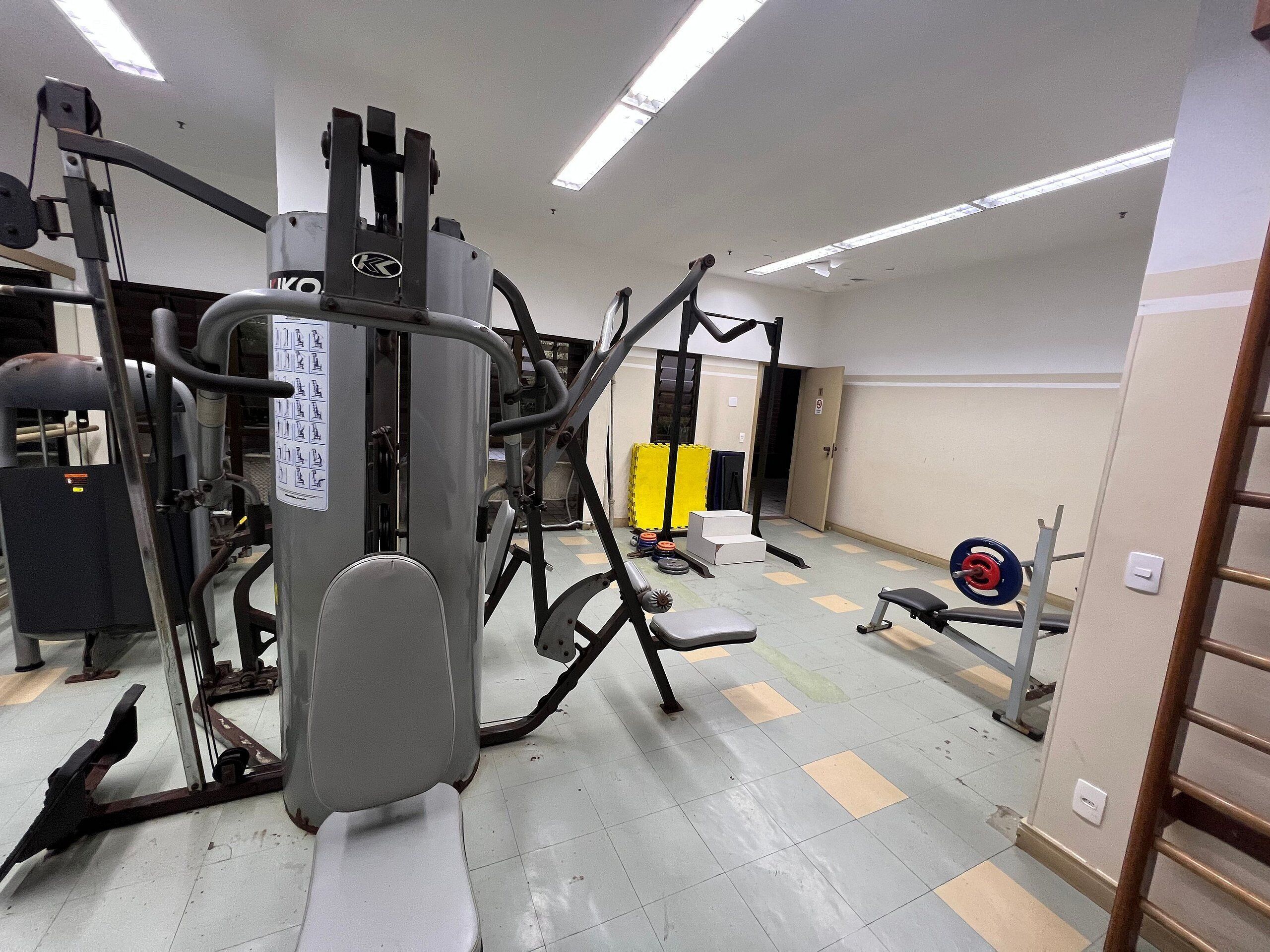 A gym with various exercise machines, a weight bench, and a squat rack.