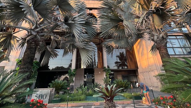 A modern building with a curved facade, surrounded by palm trees and a well-maintained garden. - Ipanema Flat - Vieira Souto 500  (Rio de Janeiro)