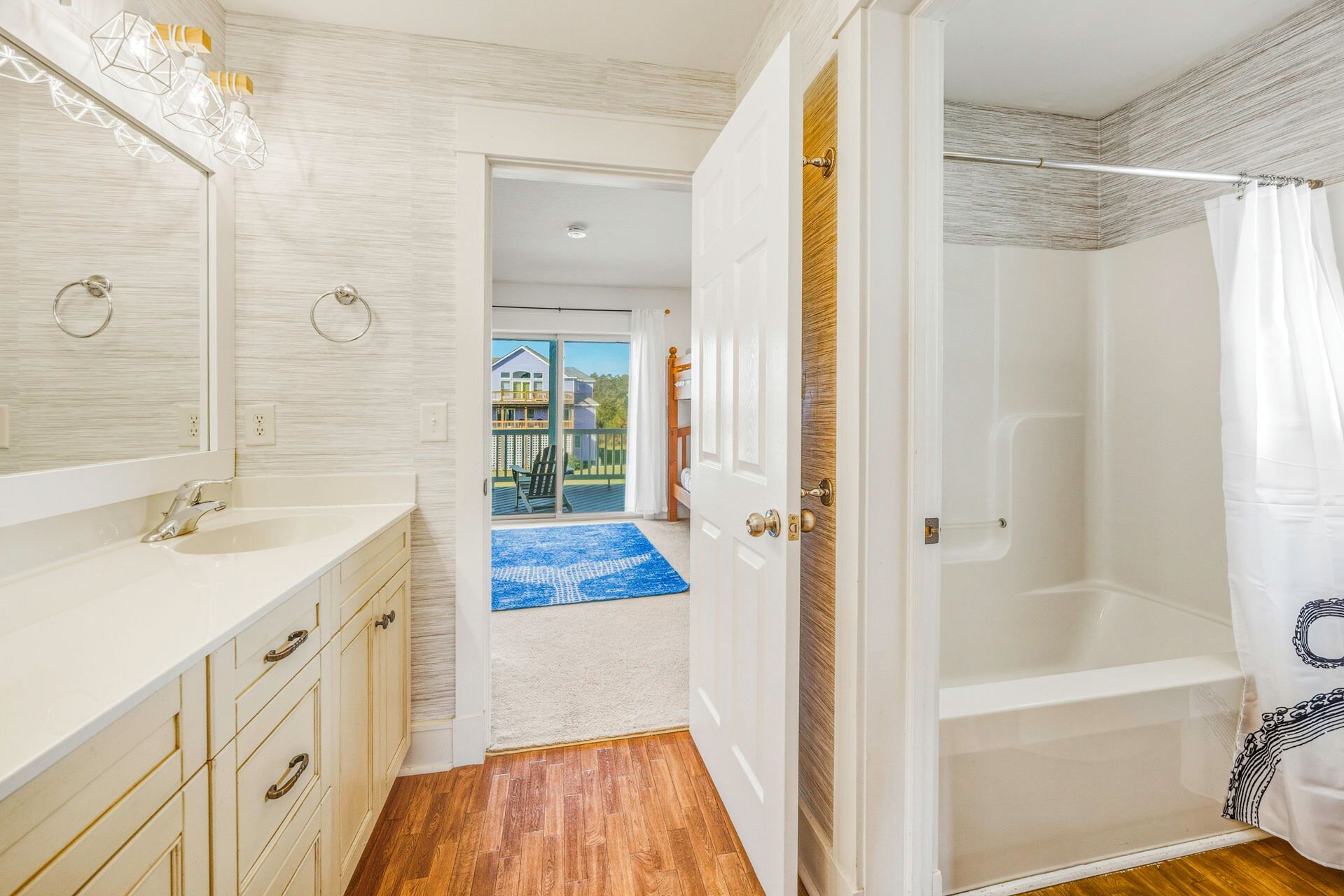 Une salle de bain avec un lavabo blanc, des meubles en bois et une douche avec un rideau blanc.