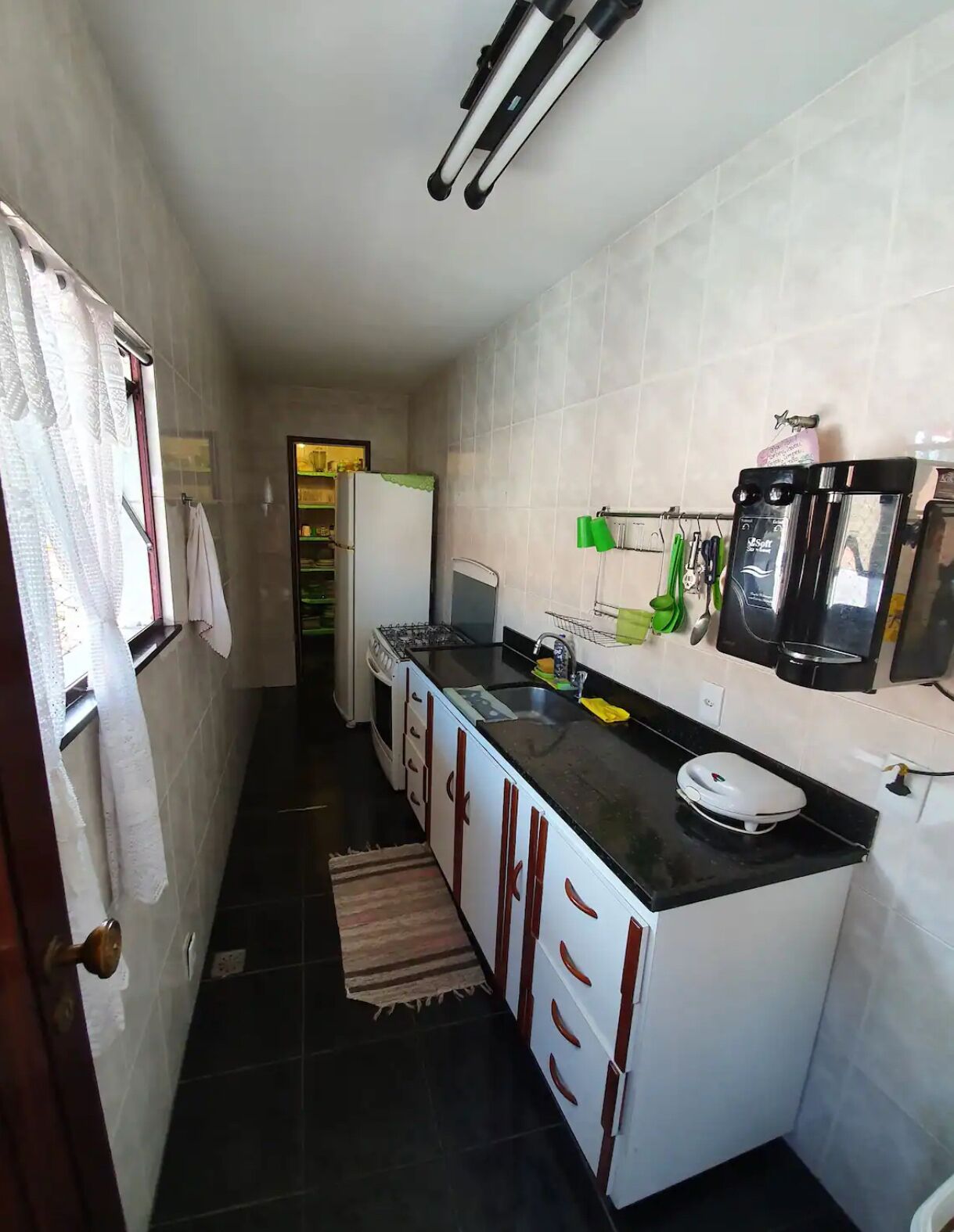 A compact kitchen with a refrigerator, stove, and coffee maker.