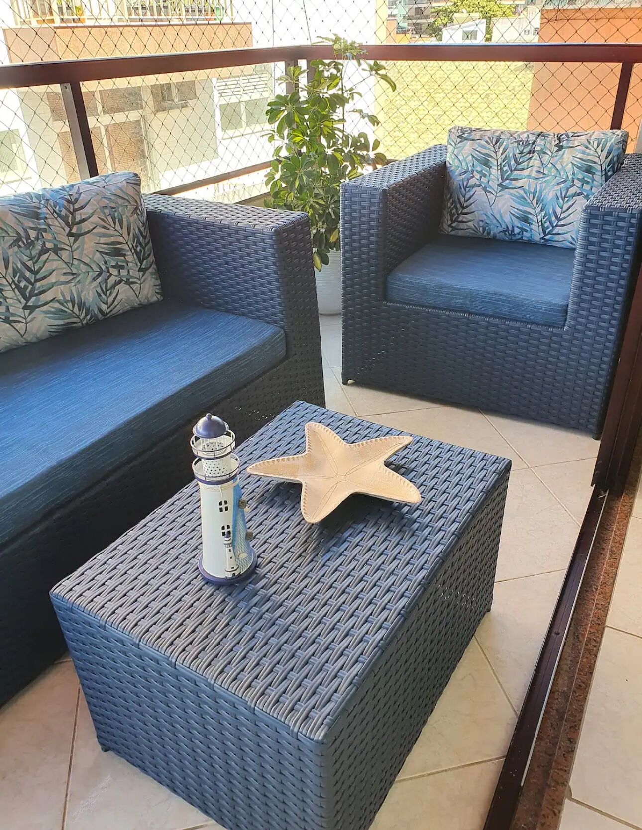 Ein Balkon mit Korbmöbeln, darunter zwei Sofas und ein Tisch mit Dekoration.