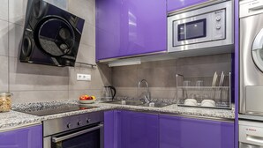 A modern kitchen with purple cabinets, stainless steel appliances, a built-in oven, and a microwave.