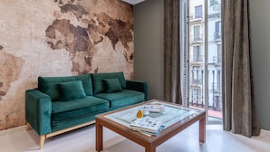 A living room with a green sofa, a glass coffee table, and a world map wall.