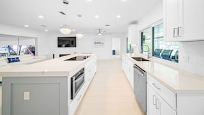 Una cocina moderna con armarios blancos, una isla central y un amplio ventanal que proporciona luz natural.