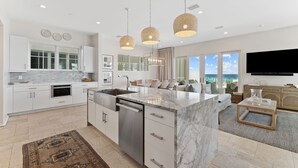 A modern kitchen with white cabinetry, a marble island, and pendant lighting.