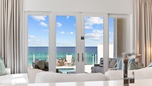 A modern hotel room with a large sliding glass door leading to a balcony with a view of the ocean.