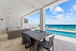 Un espace extérieur abrité comprenant une piscine, une table à manger avec des chaises et un canapé.