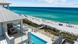 A beach resort with a pool, beach chairs, and umbrellas.