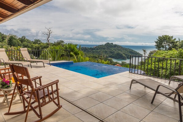 Zona de piscina en la azotea con vistas al océano y las colinas.