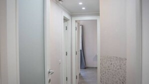 A narrow hallway with white walls and a tiled floor.