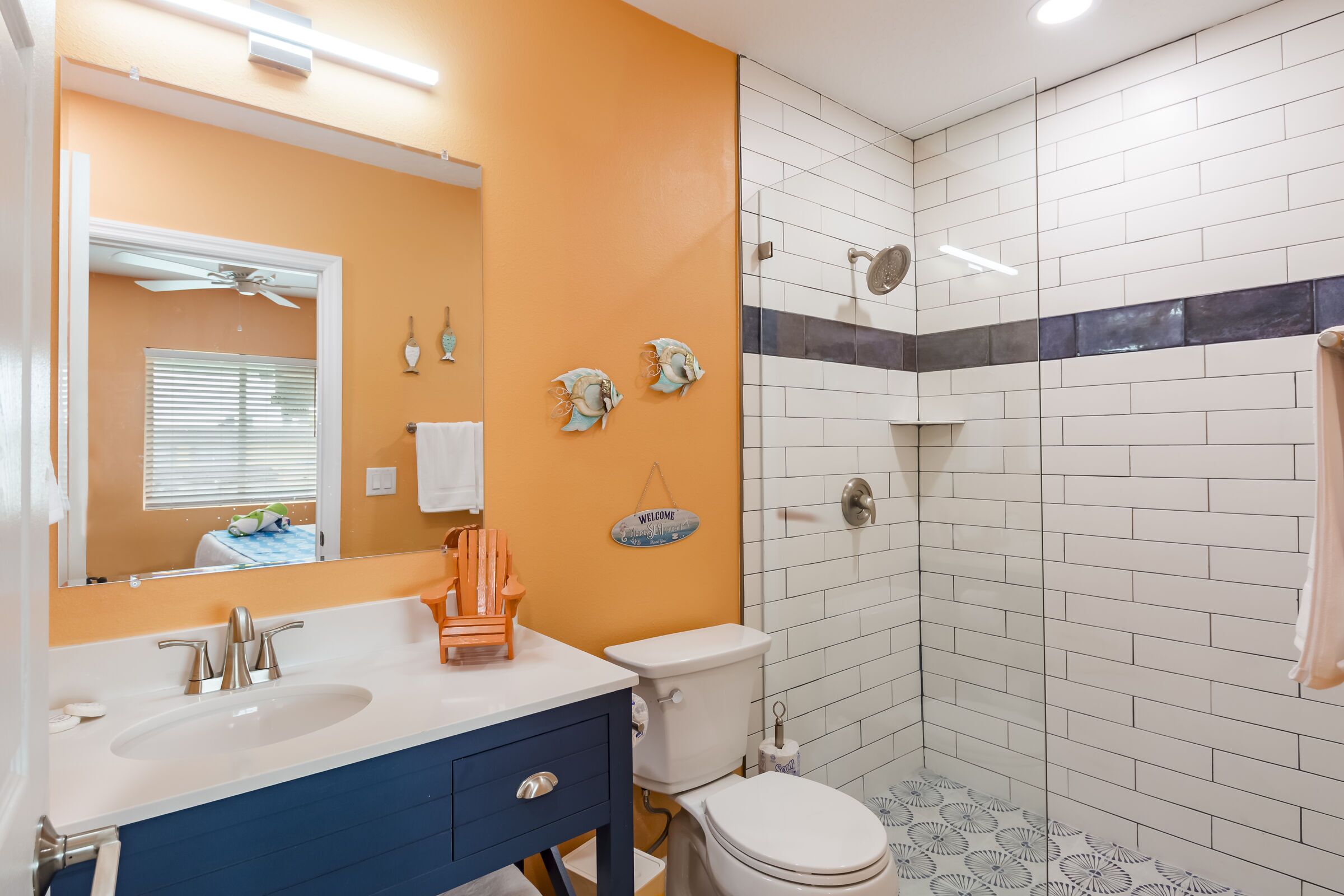 Un baño con lavamanos blanco, tocador azul y cabina de ducha de vidrio.