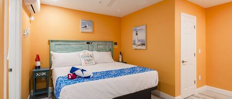 A bedroom with a bed, a nightstand, a ceiling fan, and a door.