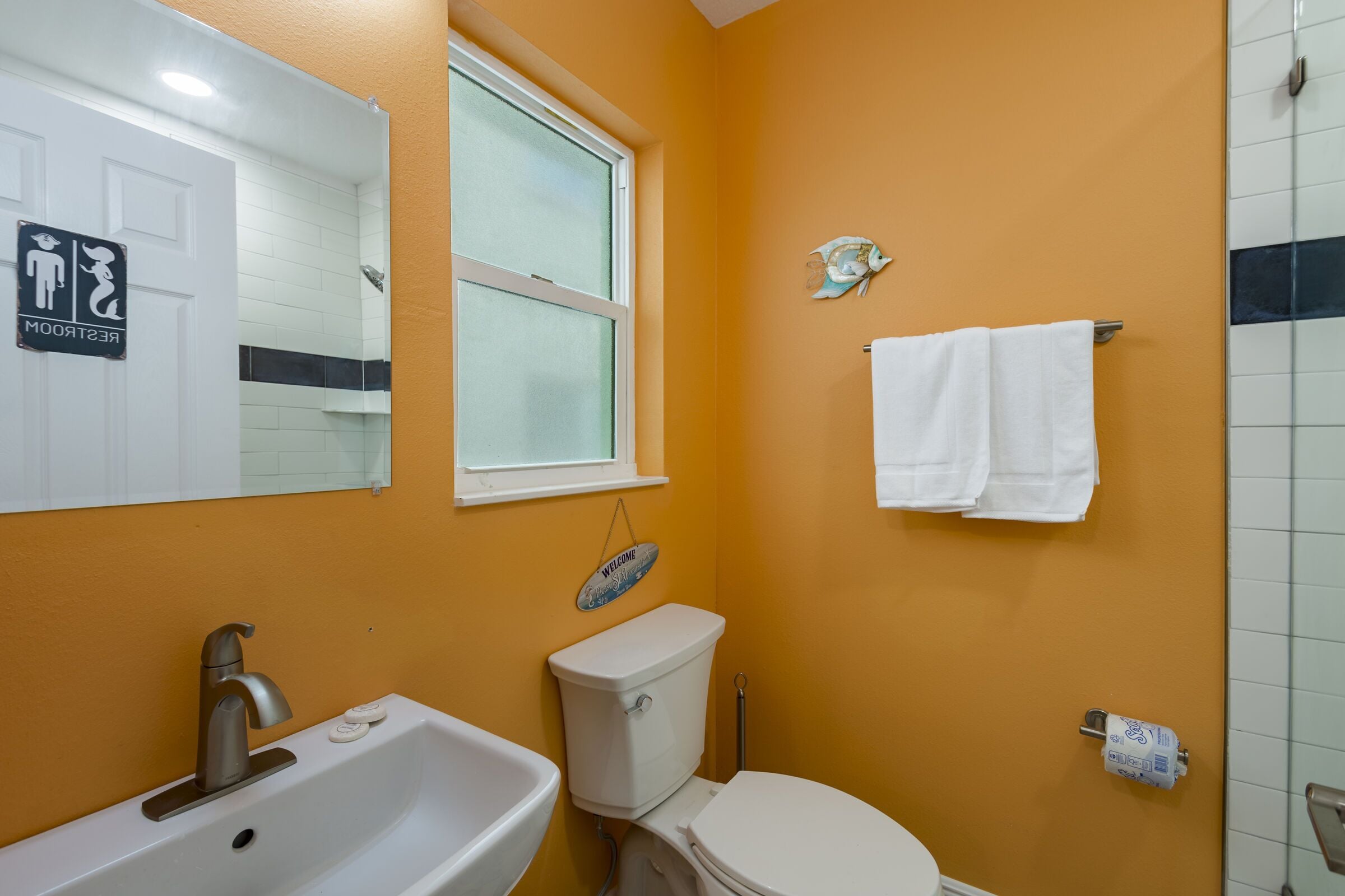 A bathroom with a white sink, toilet, and a window.