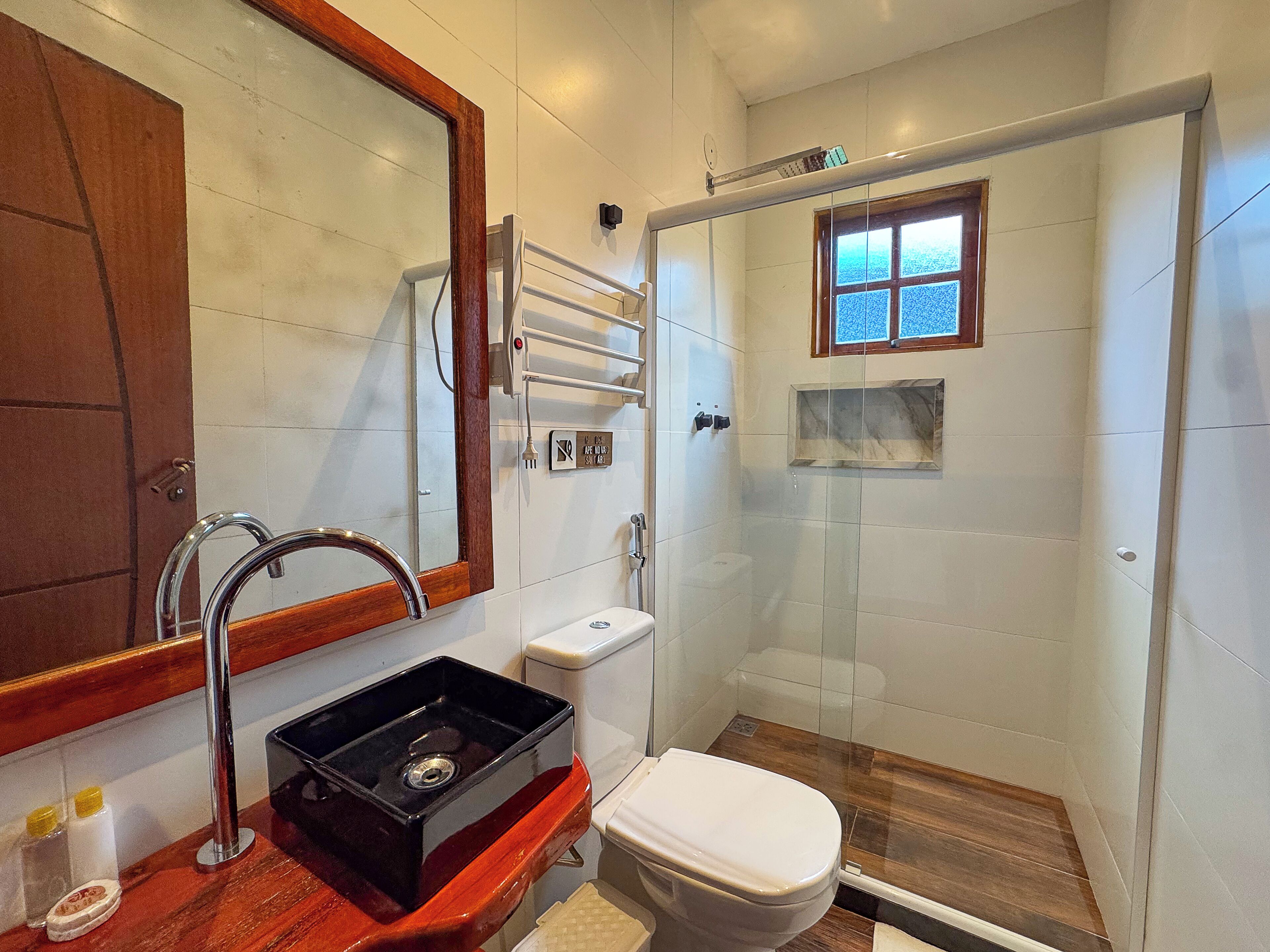 A bathroom with a shower, toilet, sink, and a large mirror.