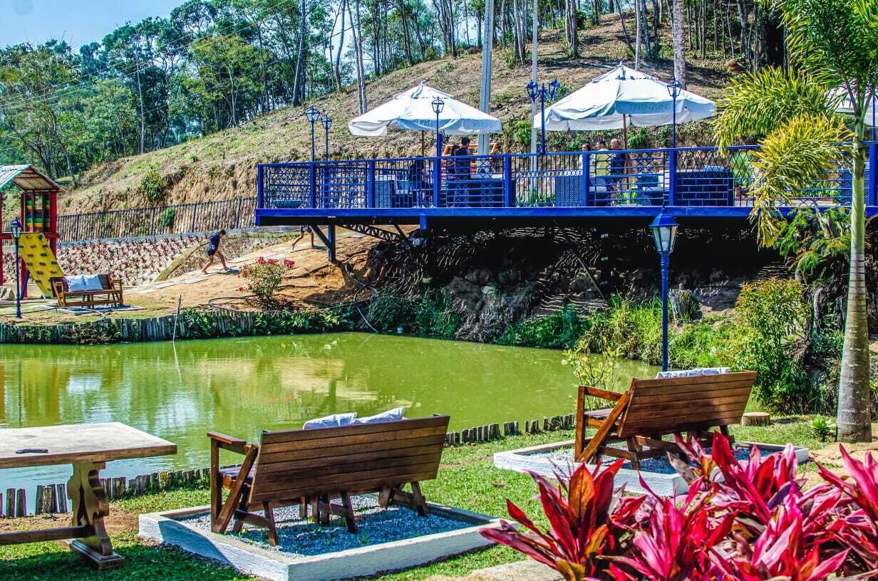 A serene outdoor area with a pond, wooden benches, and a blue bridge.