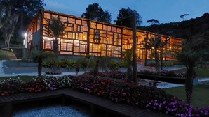 A modern building with large windows and a wooden deck in front. -  Art Green (Teresópolis)