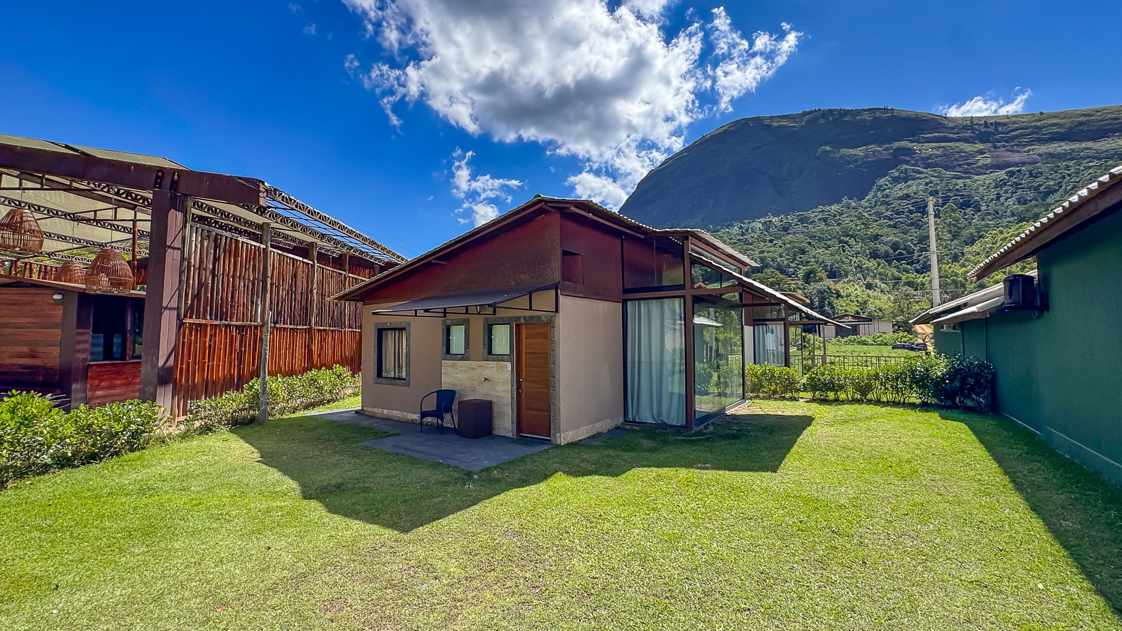A modern house with a small patio, a wooden fence, and a mountain in the background.