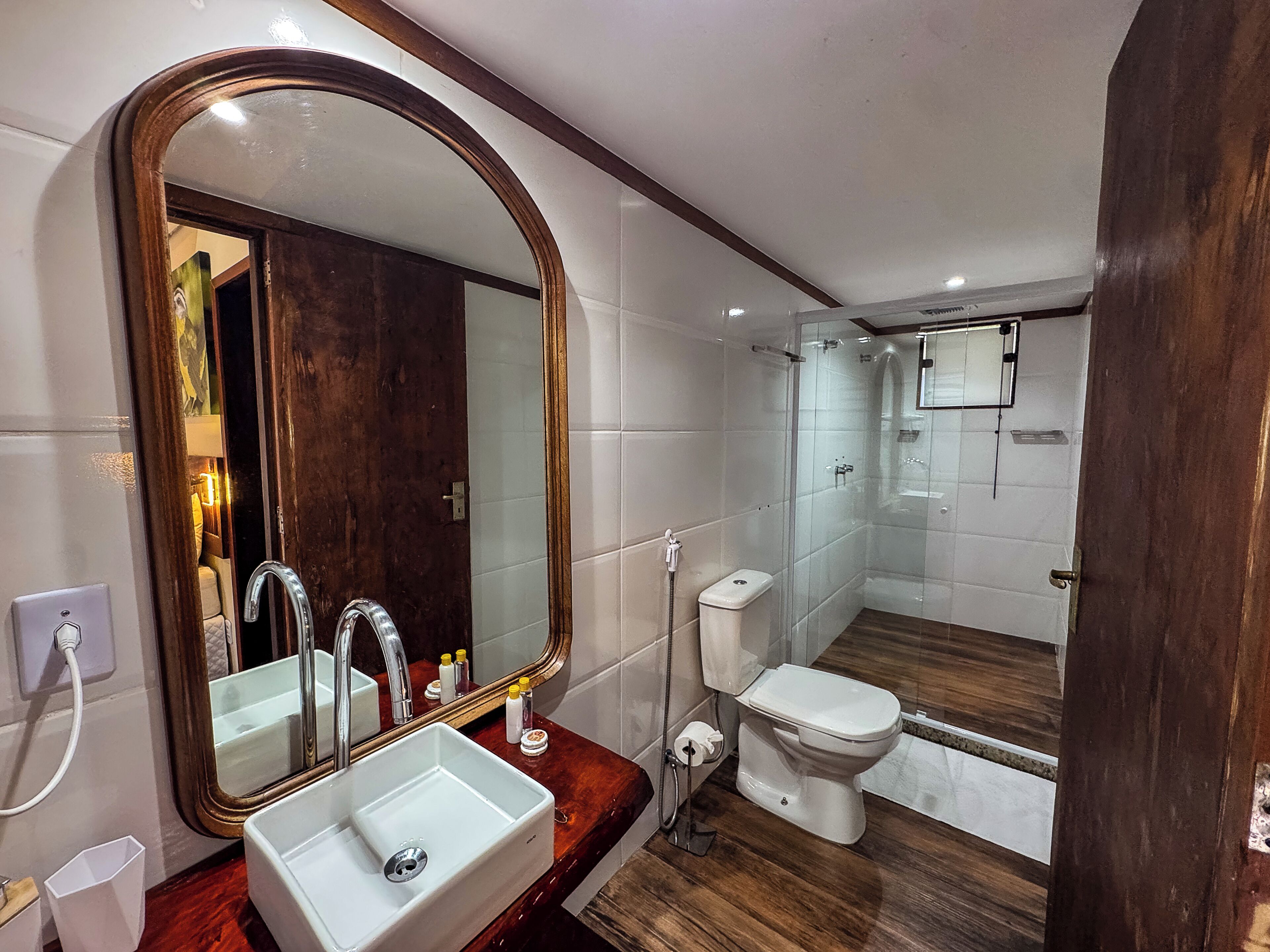 Une salle de bain avec un grand miroir, un lavabo, des toilettes et un espace douche.
