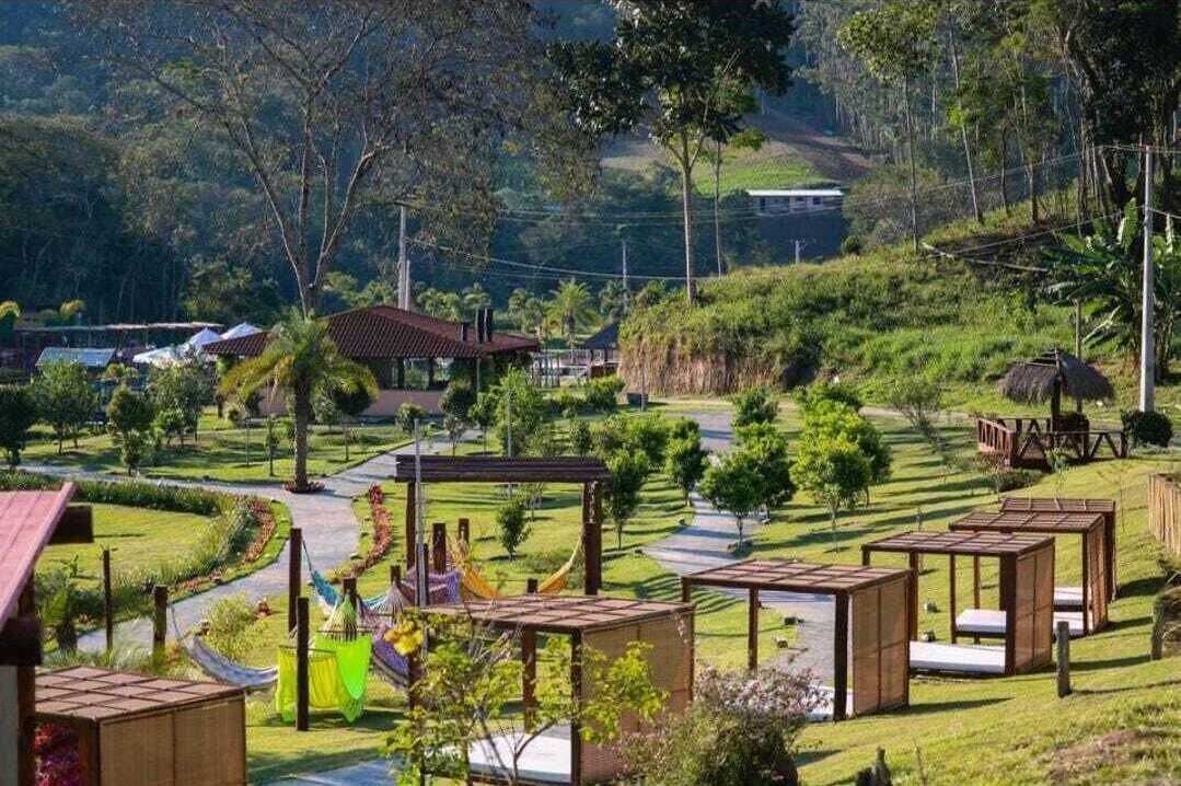 Un cadre rural avec un chemin bien défini, des constructions en bois et de la verdure.