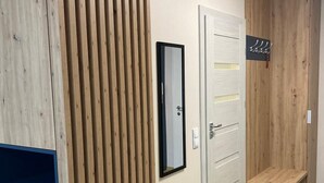 Un couloir avec des lambris en bois, une porte blanche, un miroir et un petit banc.