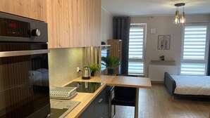 Une cuisine moderne avec des meubles de rangement en bois, un four encastré et une machine à café posée sur le plan de travail.