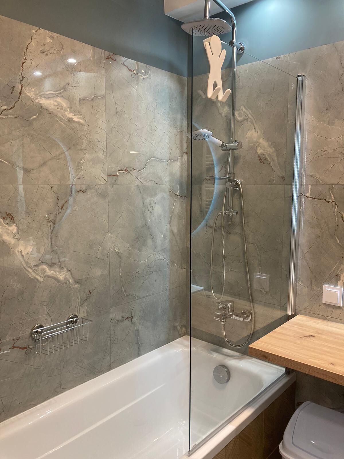 A modern bathroom with a glass-enclosed shower, a white bathtub, and a wooden vanity.