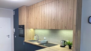 Une cuisine moderne avec des meubles en bois, un four encastré, un évier et une bouilloire.