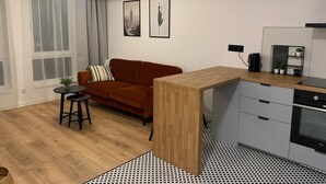 Un espace de vie moderne comprenant une table à manger en bois, un canapé, une petite table d’appoint et un coin cuisine avec une cuisinière.