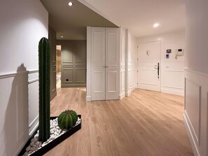 Un pasillo con puertas blancas, una planta de cactus y piso de madera.