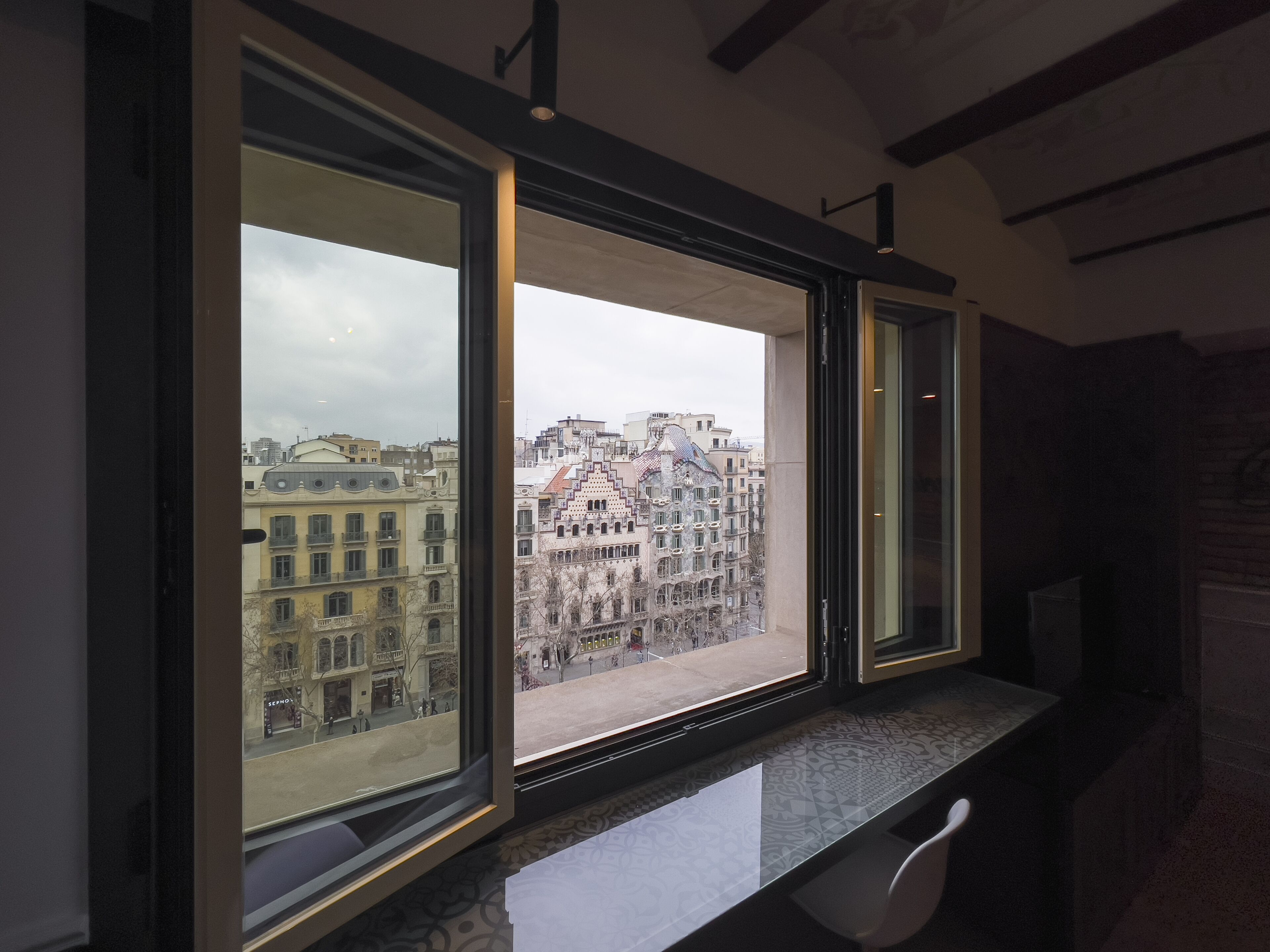 Habitación con amplias ventanas que dan a un paisaje urbano, con una mezcla de edificios modernos e históricos.