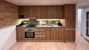 Una cocina compacta con armarios de madera, un microondas, un horno empotrado y un lavamanos.