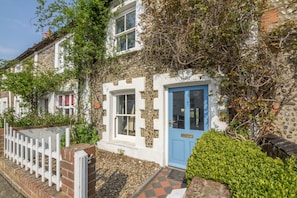 A traditional stone house with a blue door, white picket fence, and a well-maintained garden. - Burnham Cottage (2) , Well-next-the-Sea, Norfolk (Wells-next-the-Sea)