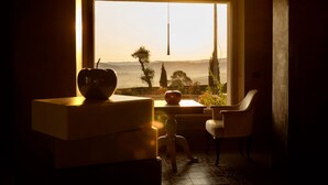A room with a large window, a table with a bowl, and a chair. - Villa Etru (Peccioli)