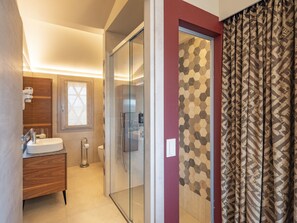 Un baño moderno con cabina de ducha de vidrio, tocador de madera y retrete.