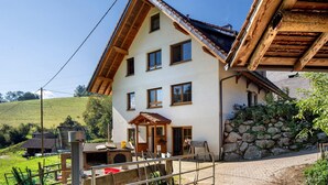 Un edificio a due piani con tetto spiovente, parete in pietra e veranda in legno.