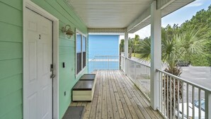 A covered porch with a bench, a door, and a blue door in the background. - 30A Getaway Too! (Santa Rosa Beach)