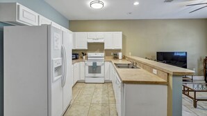 A modern kitchen with white cabinetry, a built-in oven, a microwave, and a sink. - 30A Getaway Too! (Santa Rosa Beach)