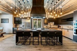 A modern kitchen with a central island, bar stools, and pendant lighting.