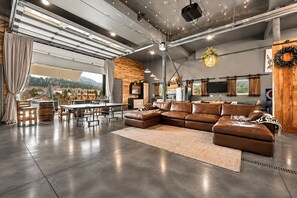 Un amplio espacio habitable con un sofá modular grande, una mesa de comedor con sillas y una cocina al fondo.