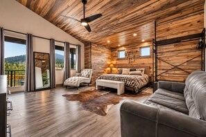 Un dormitorio amplio con una cama grande, una zona de estar con un sofá, una silla y vistas al exterior.
