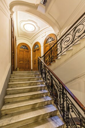 A grand staircase with ornate black railings and wooden doors. - Amedeo Apartment by Wonderful Italy (Naples)