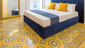 Une chambre d’hôtel avec un lit, un miroir, une fenêtre et un sol à motifs.