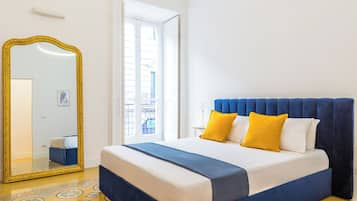 Quarto com uma cama grande, um espelho e soalho estampado.