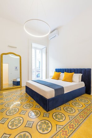 A bedroom with a large bed, a mirror, and patterned flooring. - Piazza Amedeo Flat by Wonderful Italy (Naples)
