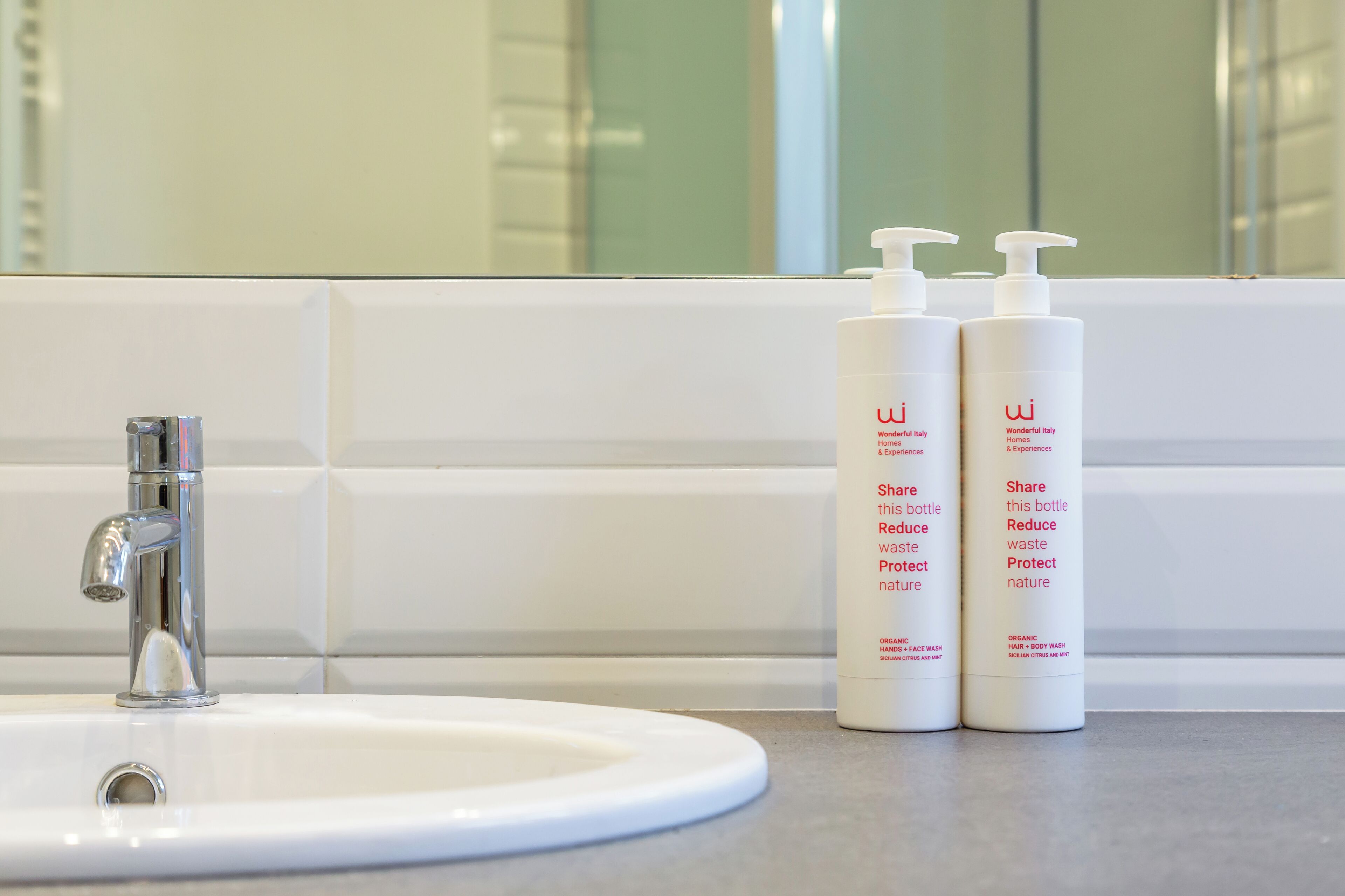 A bathroom sink with two white bottles labeled 'Wonderful Italy Homes & Experiences' on a countertop.