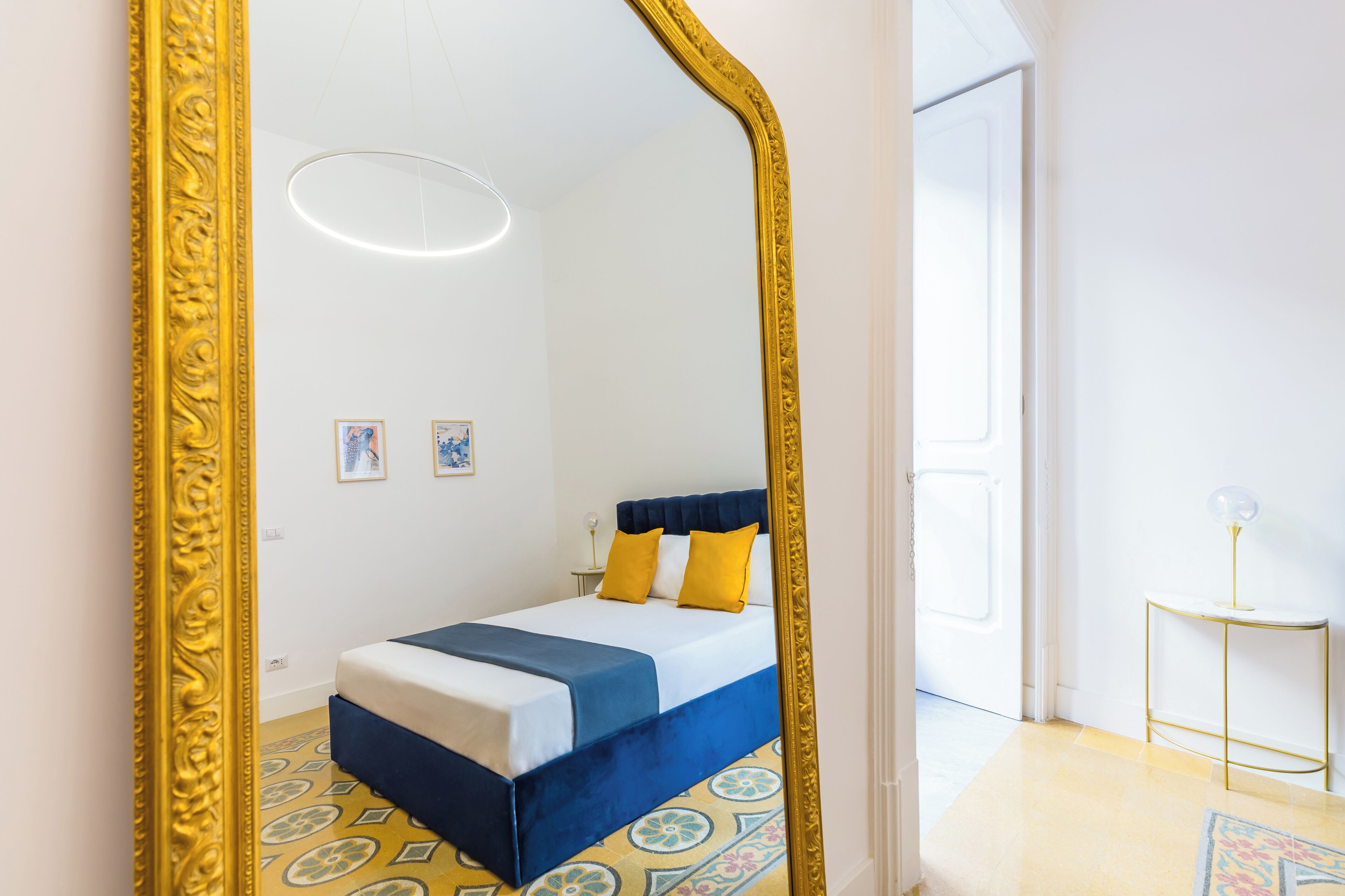 Une chambre à coucher avec un lit, un grand miroir et une petite table.