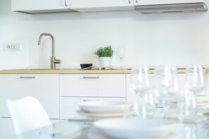 A modern kitchen with white cabinets, a stainless steel sink, and a dining area with a glass table set for a meal.