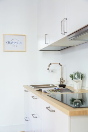 A modern kitchen with white cabinets, a wooden countertop, a stainless steel sink, and a framed sign on the wall. - Amedeo Apartment by Wonderful Italy (Naples)