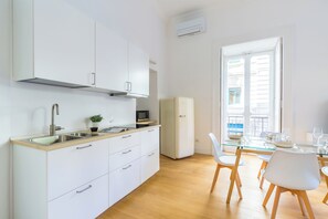 Une cuisine moderne avec des armoires blanches, un évier en acier inoxydable et un four à micro-ondes encastré.
